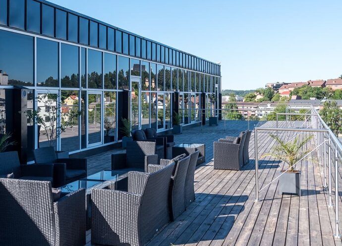 Loungemöbler på takterrassen på K7 Community, solen skiner och mot det blå himlen syns utsikten över de södra delarna av Borås