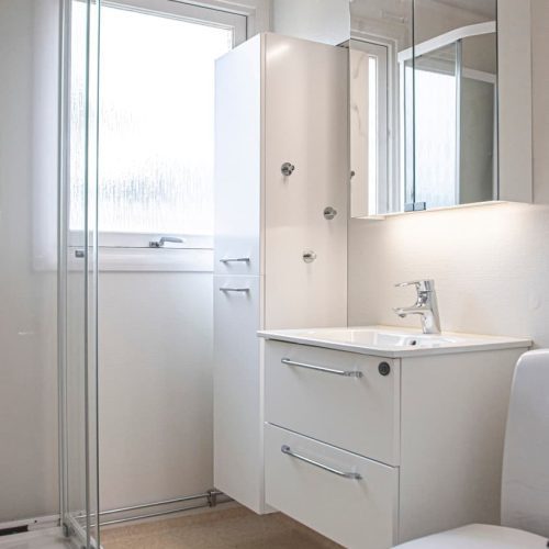 Fräsch toalett med ny kommod och högskåp, samt dusch.