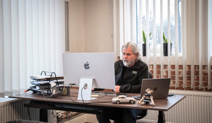 Kontor med ljusinsläpp i två väderstreck. Vd Stephan Burman sitter vid ett skrivbord och arbetar framför en datorskärm.