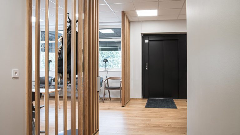 Ett ljust väntrum för patienter med fönster i två väderstreck och träspalje för lite avskärmning.